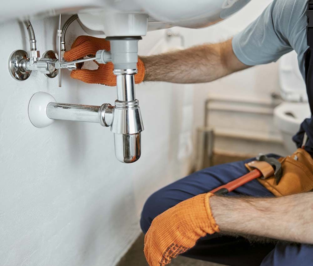 Un fontanero está arreglando un lavabo en un baño.