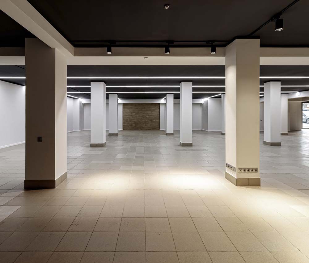 Una gran habitación vacía con columnas y luces en el techo.