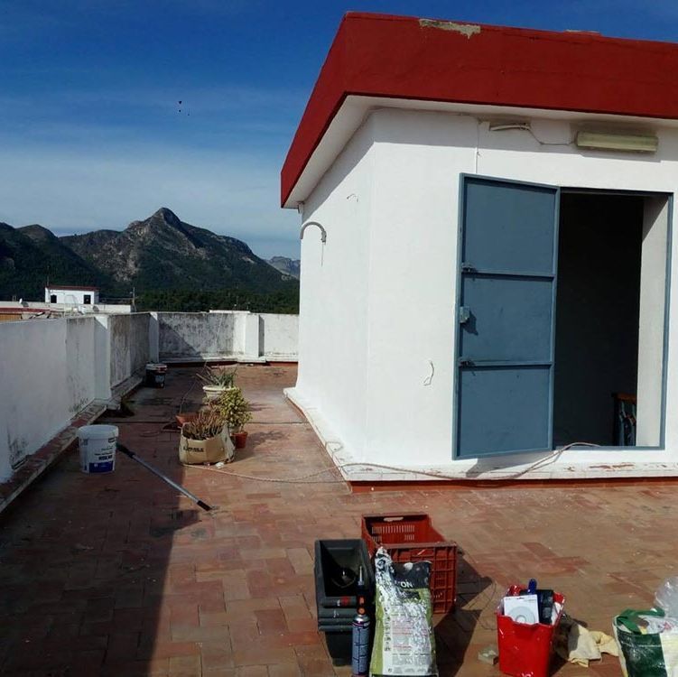 Un edificio blanco con techo rojo se encuentra en una azotea.