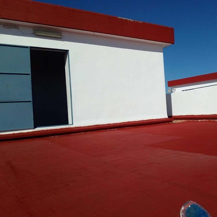 Un edificio blanco con un techo rojo y una puerta azul.