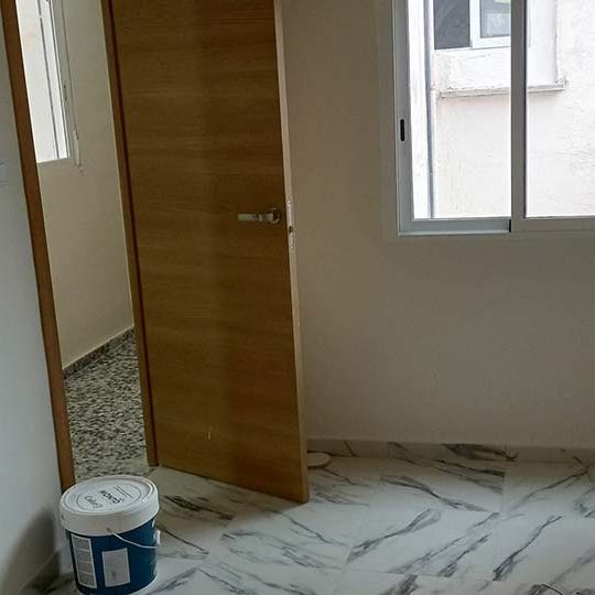 Un cubo de pintura está en una habitación al lado de una puerta.