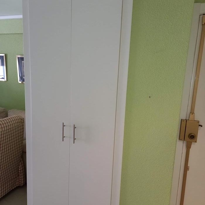 Un armario blanco en una sala de estar al lado de una puerta.