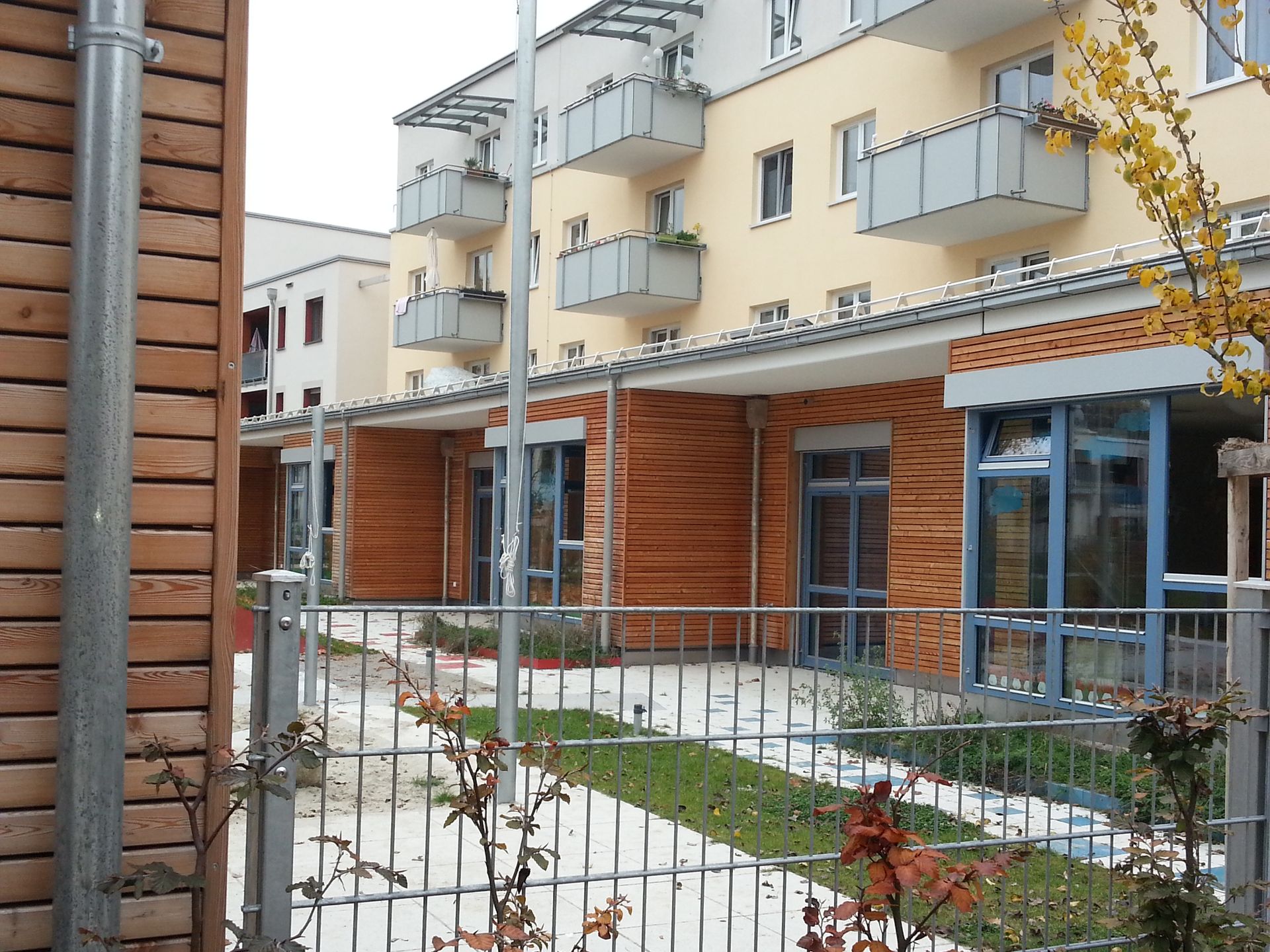Gebäude in gelb, grau und mit Holz verkleidet, Balkone stehen hervor