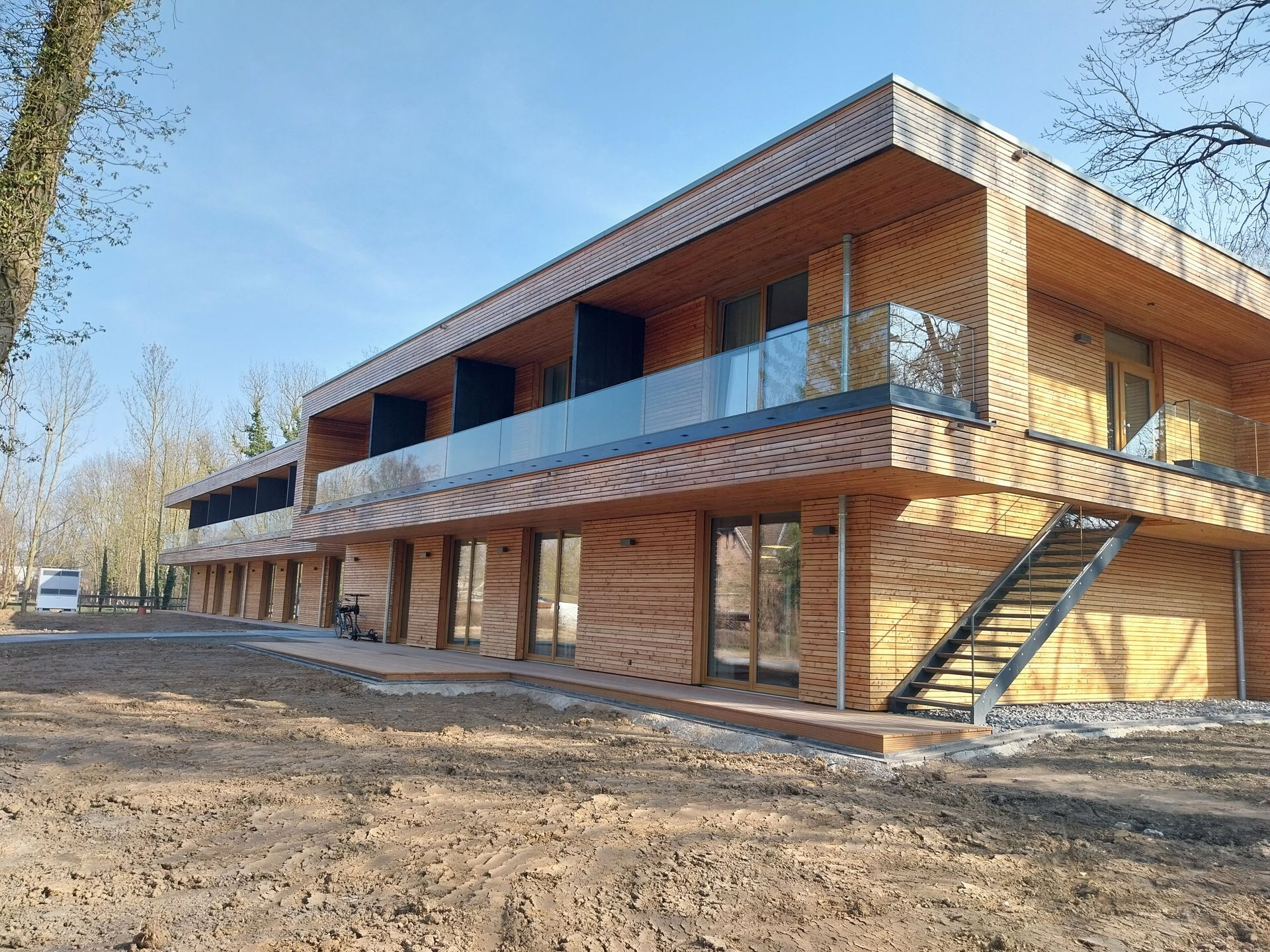 Breite Gebäude mit Holzverkleidung außen und einer Terrasse, die mit Glas umsäumt ist