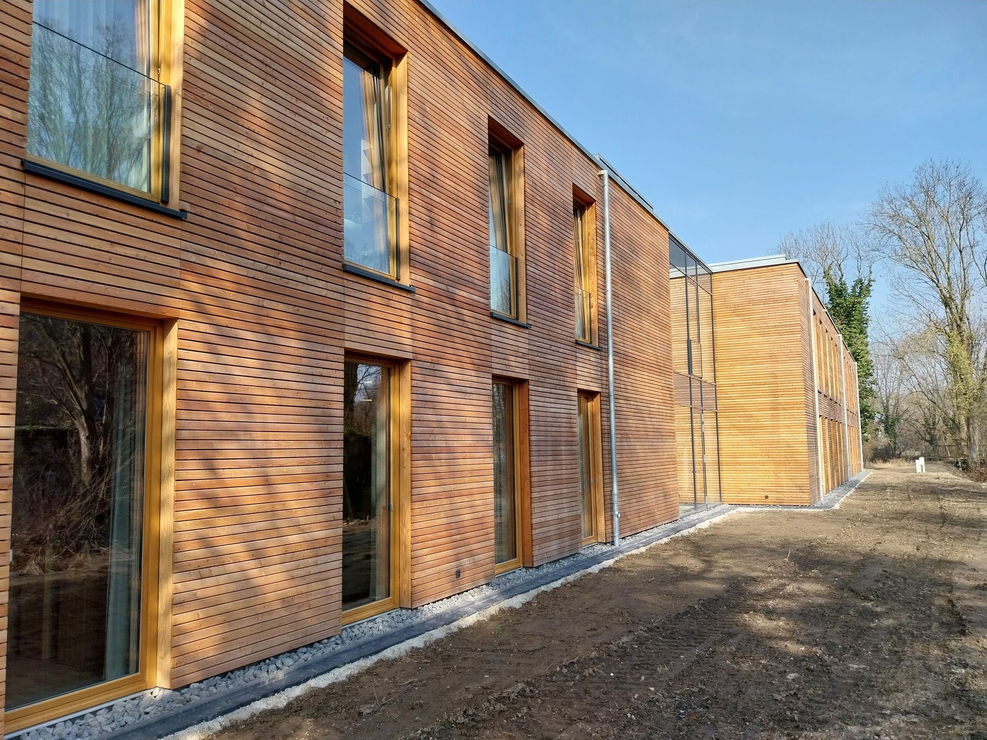 Seitenansicht eines holzvertäfelten Gebäudes mit bodentiefen Fenstern