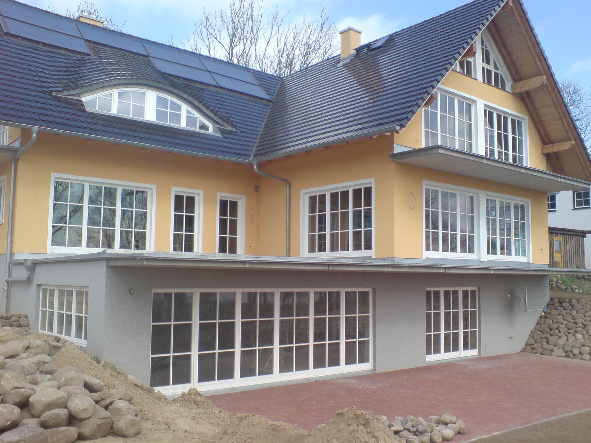 Seitliche Ansicht: Großes gelbes Haus über mehrere Etagen. Große weiße Fenster mit Fenstersprossen.
