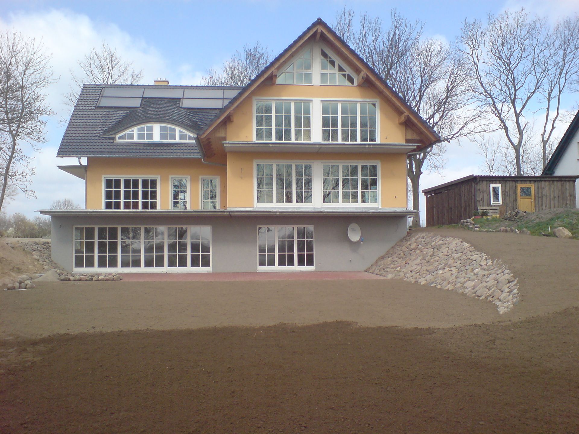 Großes gelbes Haus über mehrere Etagen. Große weiße Fenster mit Fenstersprossen.