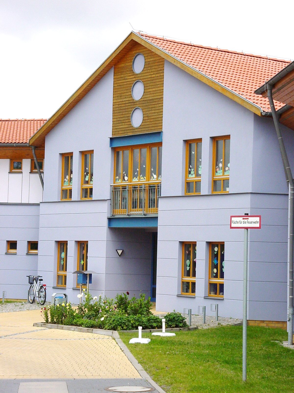 Eingang eines hellblauen Gebäudes mit Holzfensterrahmen