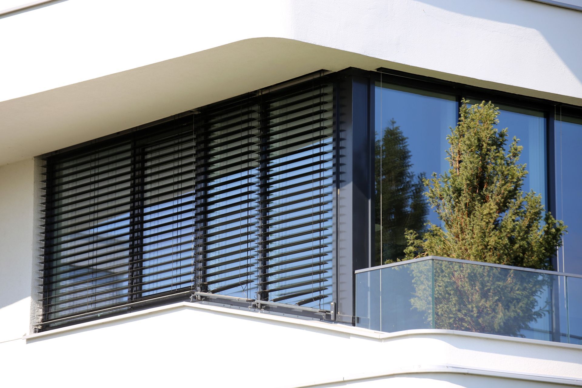 Eine schwarze Jalousie außen am Fenster als Sonnenschutz