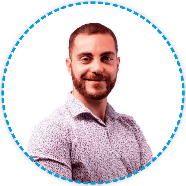 Hombre con barba sonriendo, vistiendo una camisa estampada, dentro de un círculo azul.