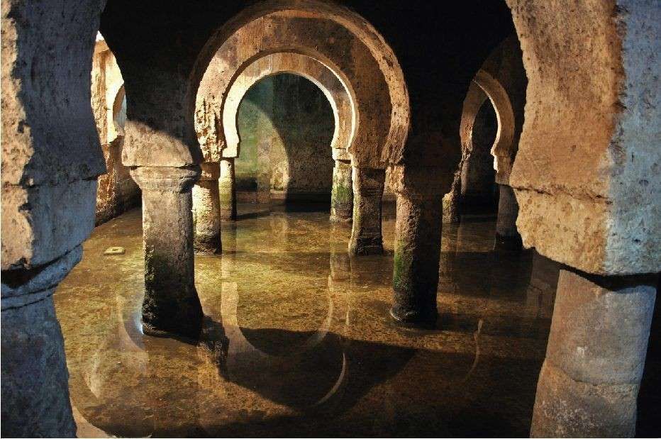 Antiguo depósito de piedra con forma de arco y agua. Los pilares sostienen los arcos, que se refleja