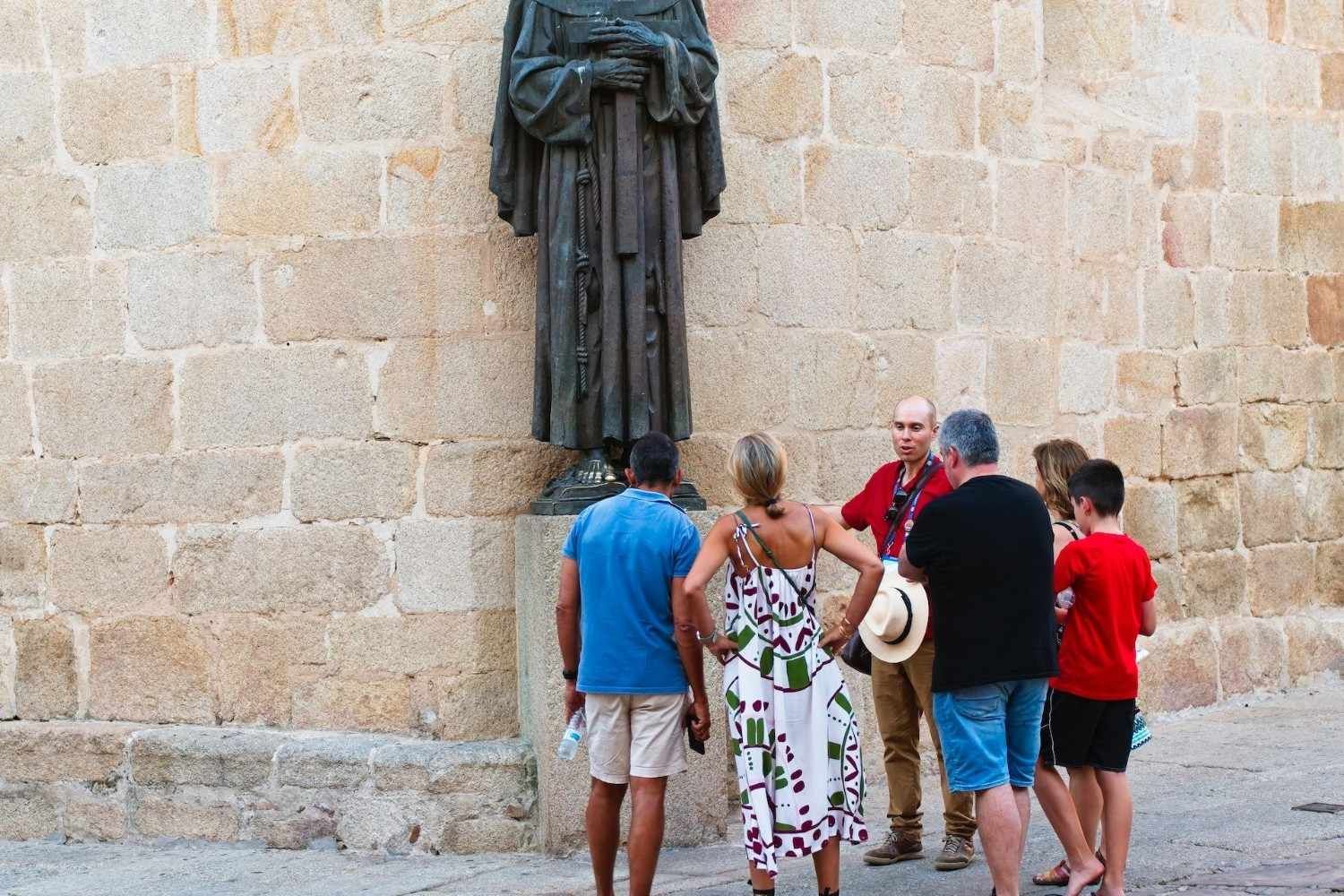 Grupo de personas mirando una estatua frente a un muro de piedra.