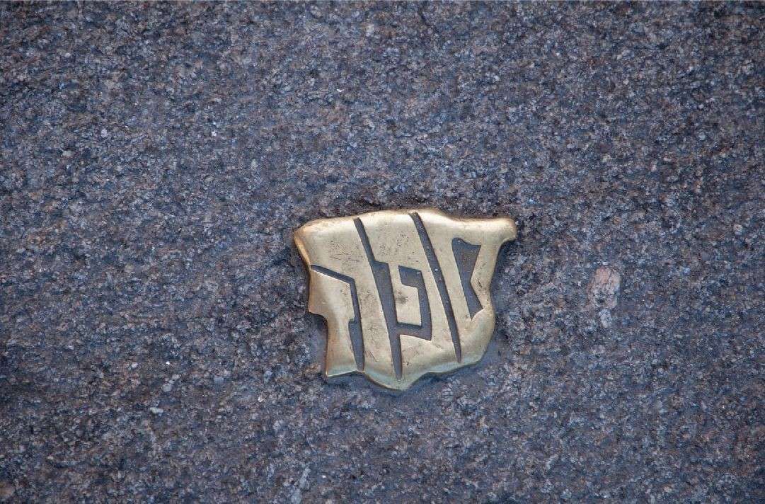 Placa de oro con letras hebreas incrustadas en piedra oscura.