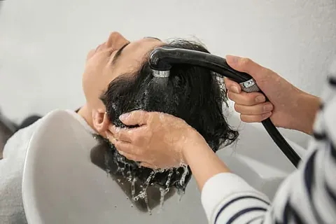 Una mujer se lava el cabello en el lavabo de una peluquería.