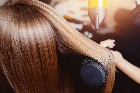 Una mujer se seca el cabello con secador en un salón.