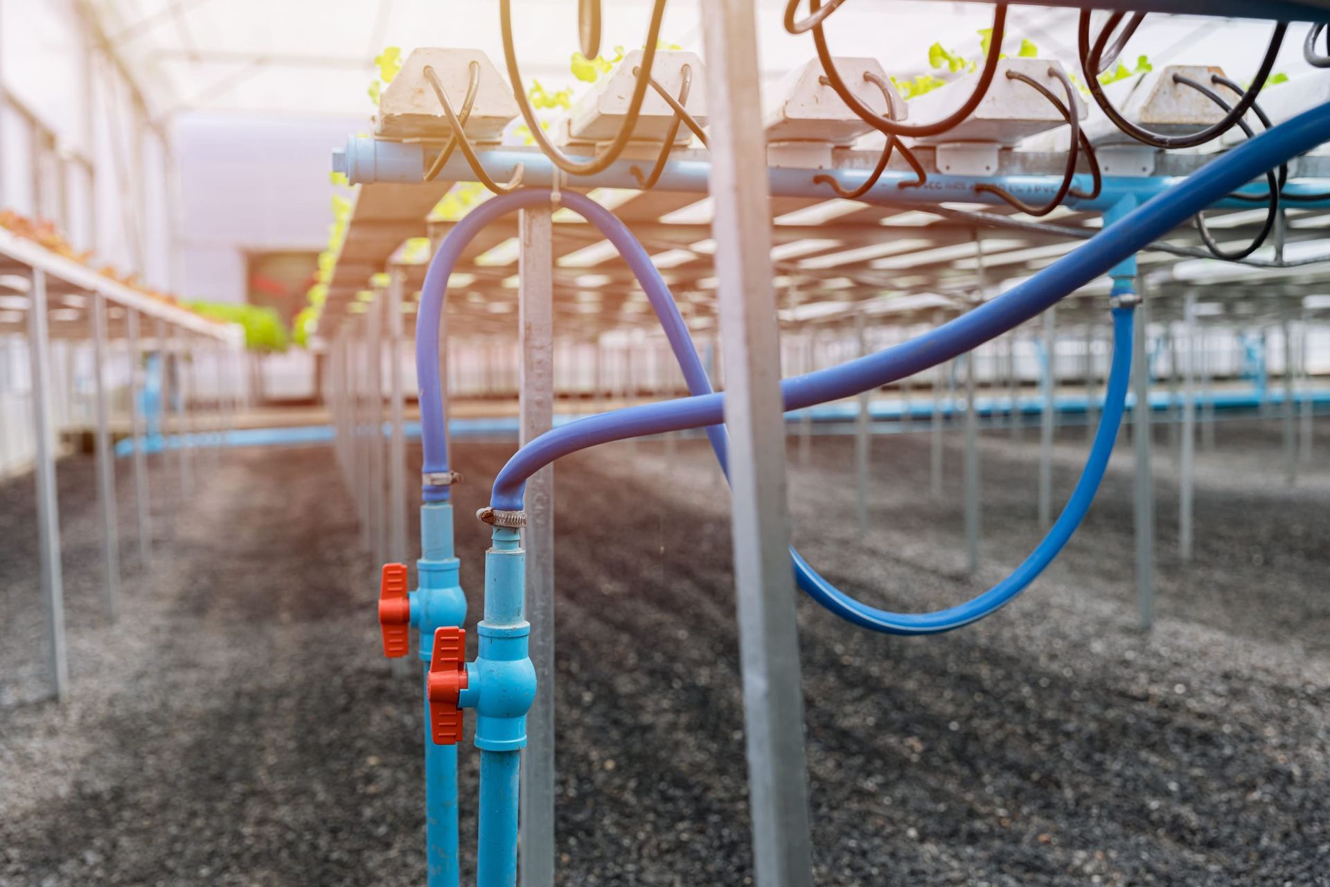 Tubos y mangueras metálicas de colores en un área de juegos de arena, con un niño al fondo.