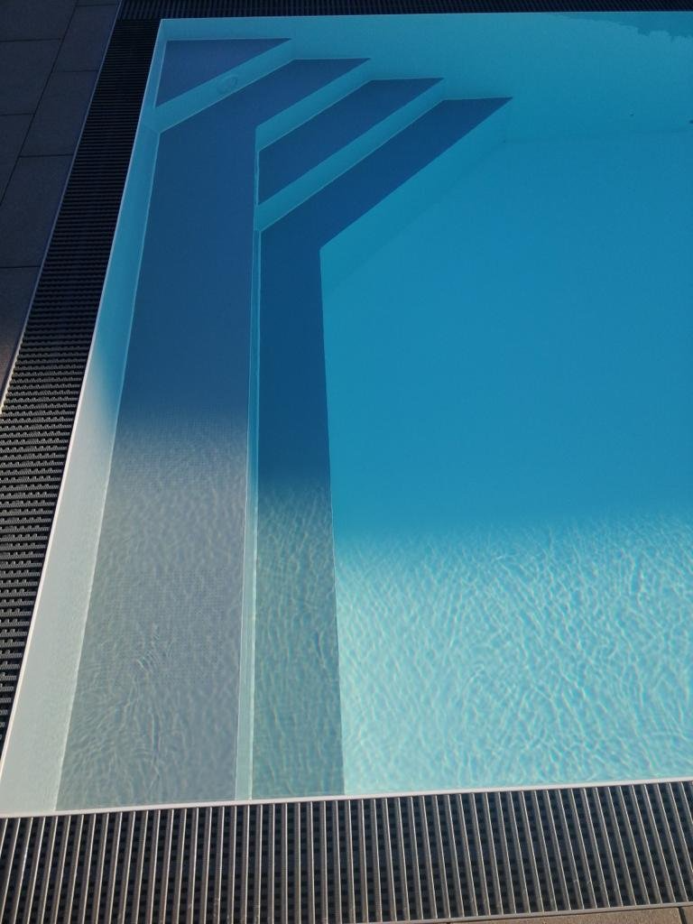 Ein Swimmingpool mit blauem Wasser und weißen Stufen