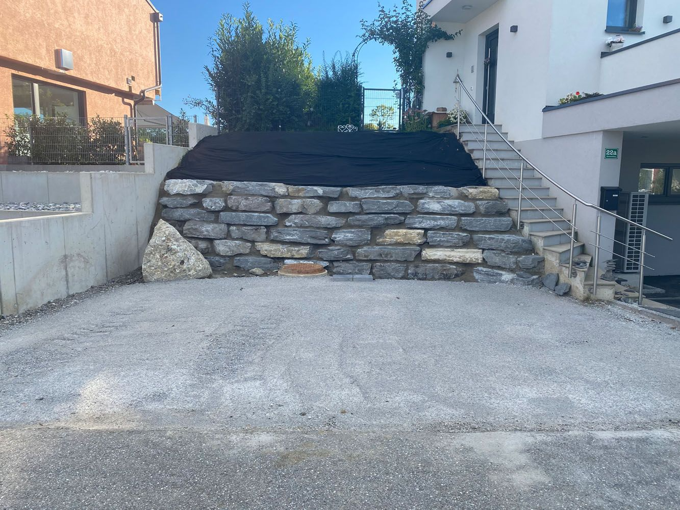 Vor einem Haus wird eine Steinmauer gebaut.