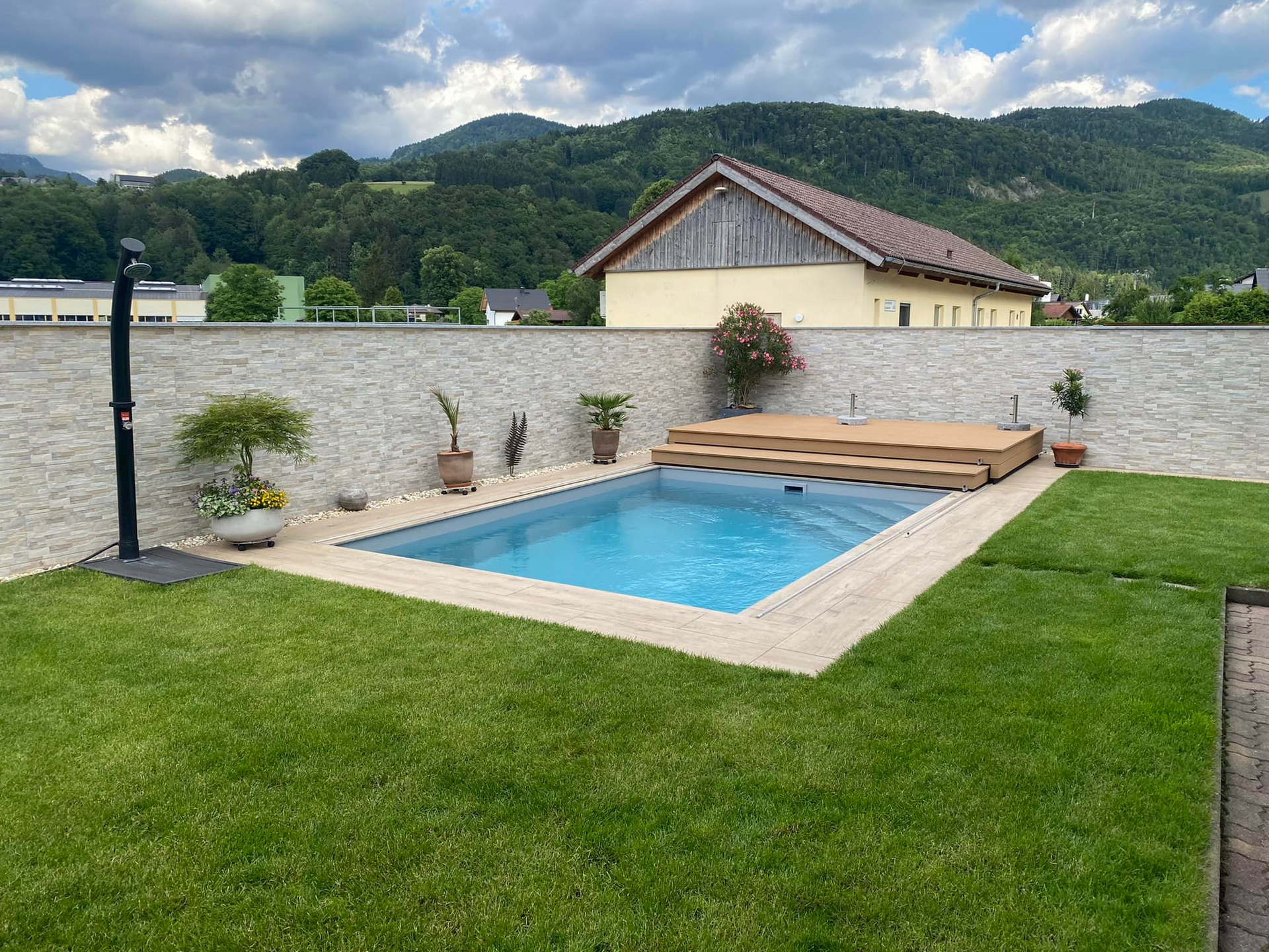 Ein kleiner Swimmingpool im Hinterhof eines Hauses mit Bergen im Hintergrund.