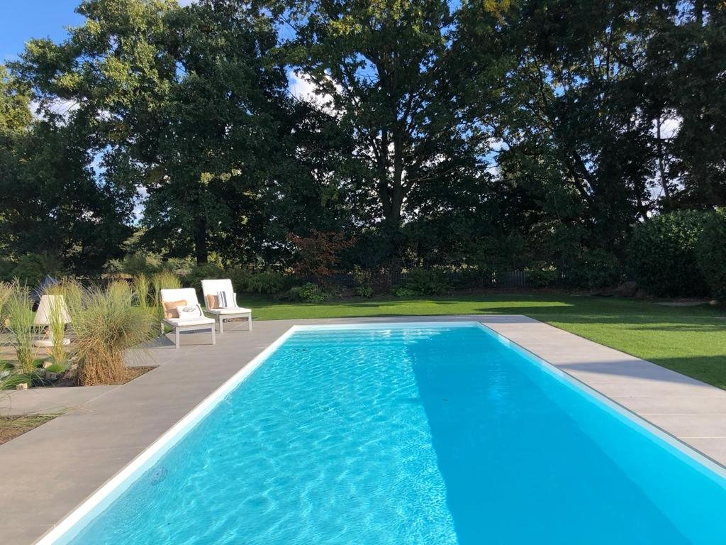 Ein großer Swimmingpool, umgeben von Stühlen und Bäumen