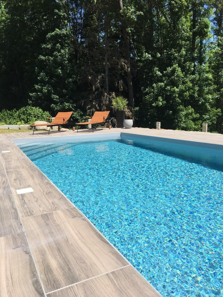 Ein großer Swimmingpool, umgeben von Bäumen und Stühlen.