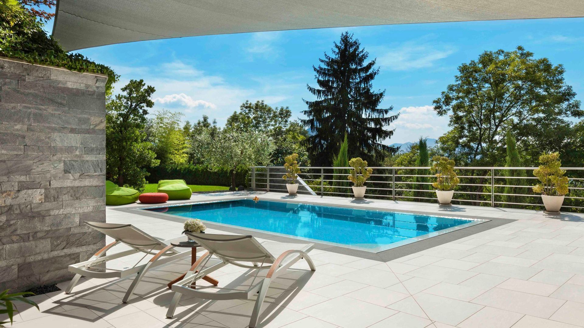 Ein großer Swimmingpool ist von Stühlen und Bäumen umgeben.