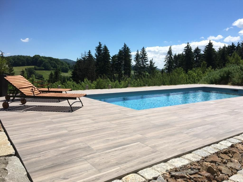 Ein großer Swimmingpool ist von einer Holzterrasse und Stühlen umgeben.