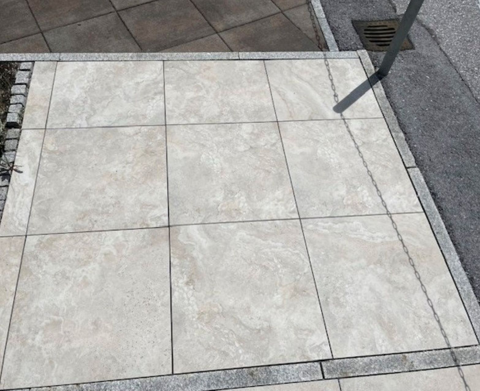 Ein gefliester Gehweg mit einem Abfluss an der Seite