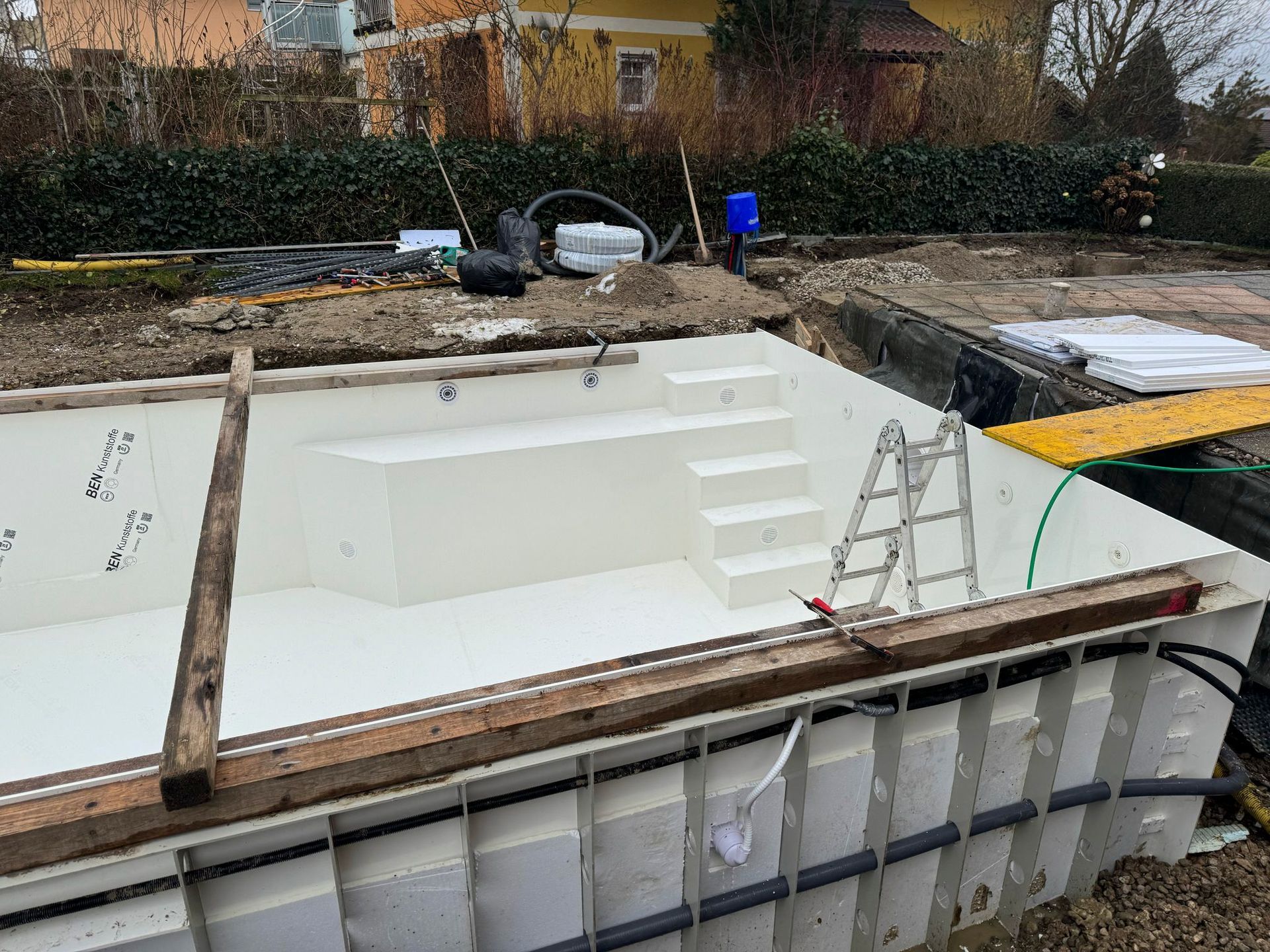 Auf einem im Bau befindlichen Schwimmbecken steht eine Leiter.