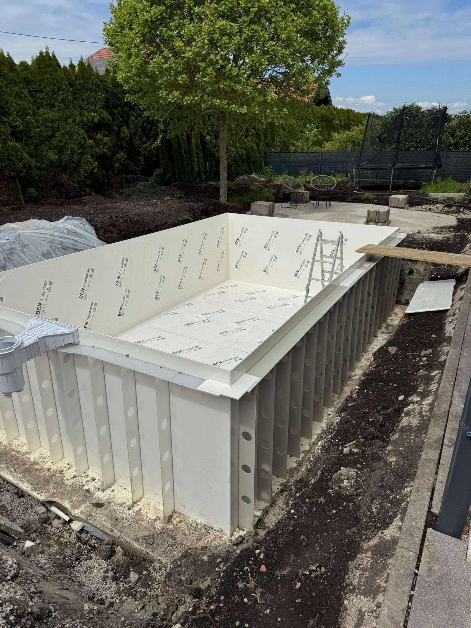 In einem Hinterhof wird ein großer weißer Swimmingpool gebaut.