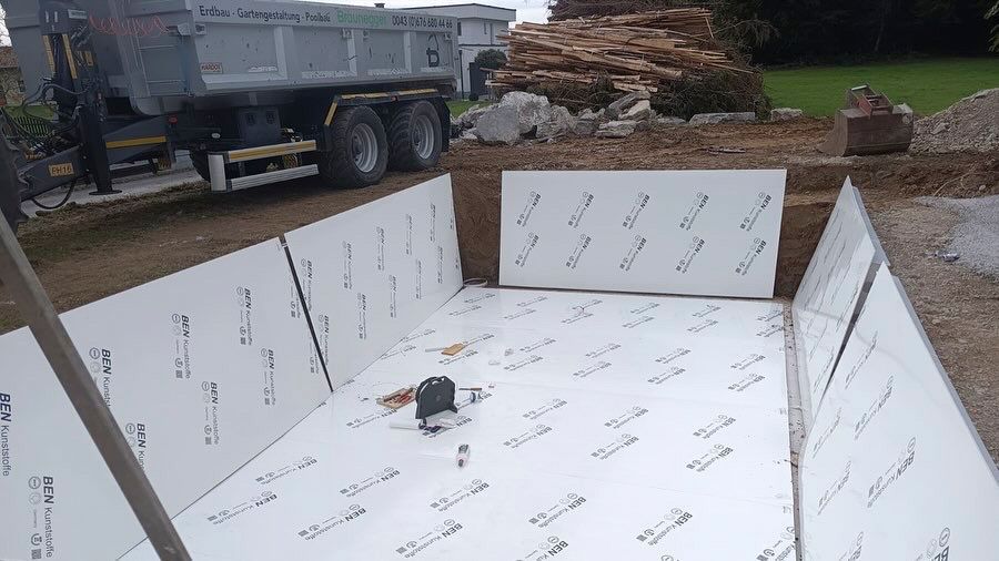 Ein Muldenkipper steht neben einem Holzstapel.