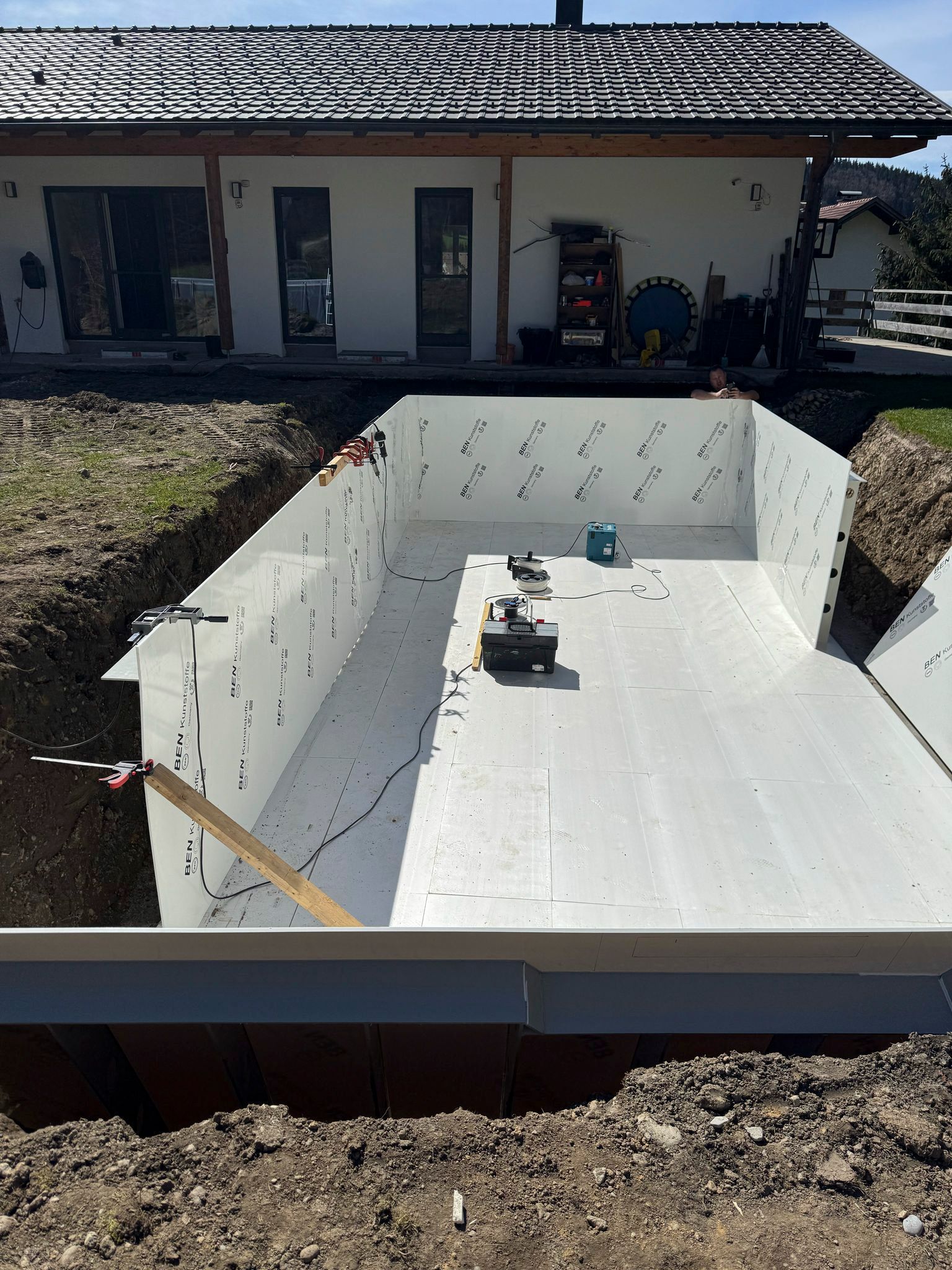 Vor einem Haus wird ein großer weißer Swimmingpool gebaut.