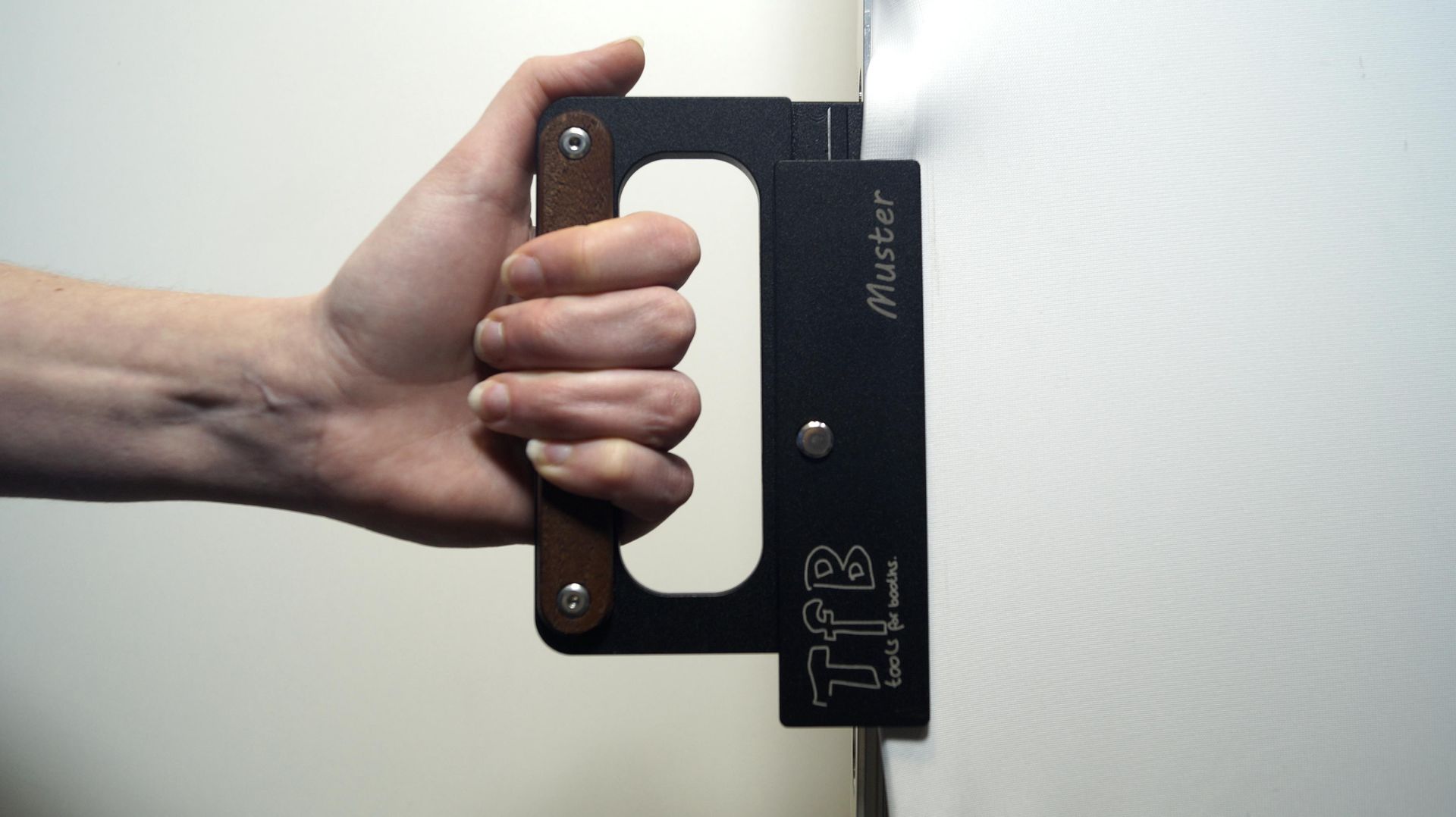 Eine Person hält ein Werkzeug mit der Aufschrift tfb darauf