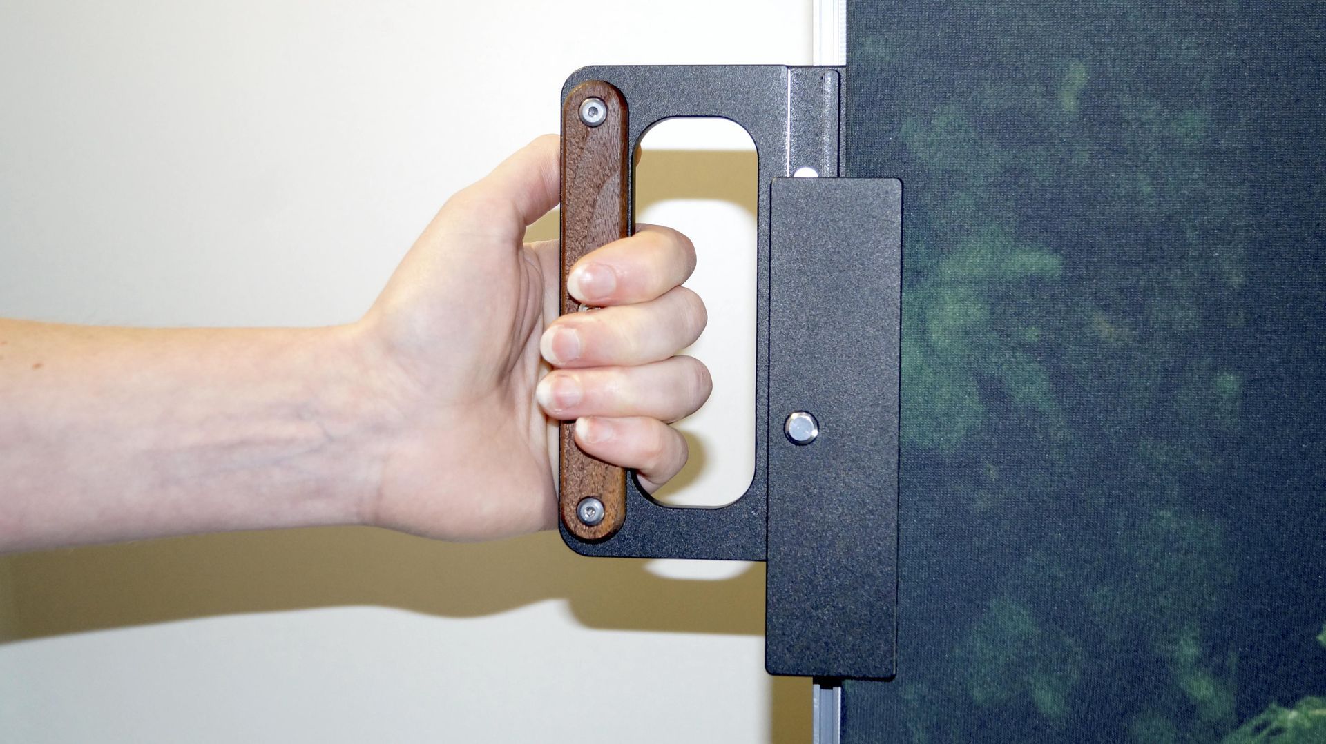 Eine Person hält eine Holzklinke an einer Tür.