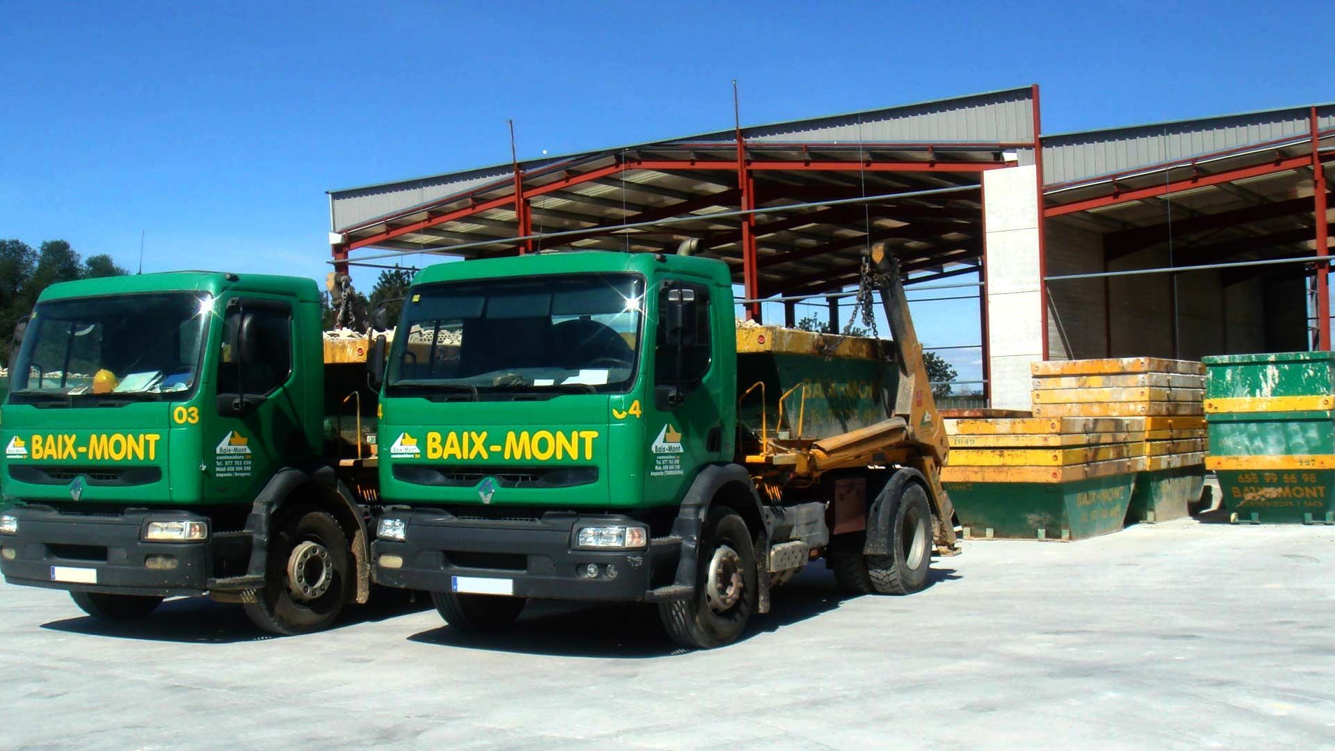 Dos camiones de carga trasera están estacionados frente a un edificio.