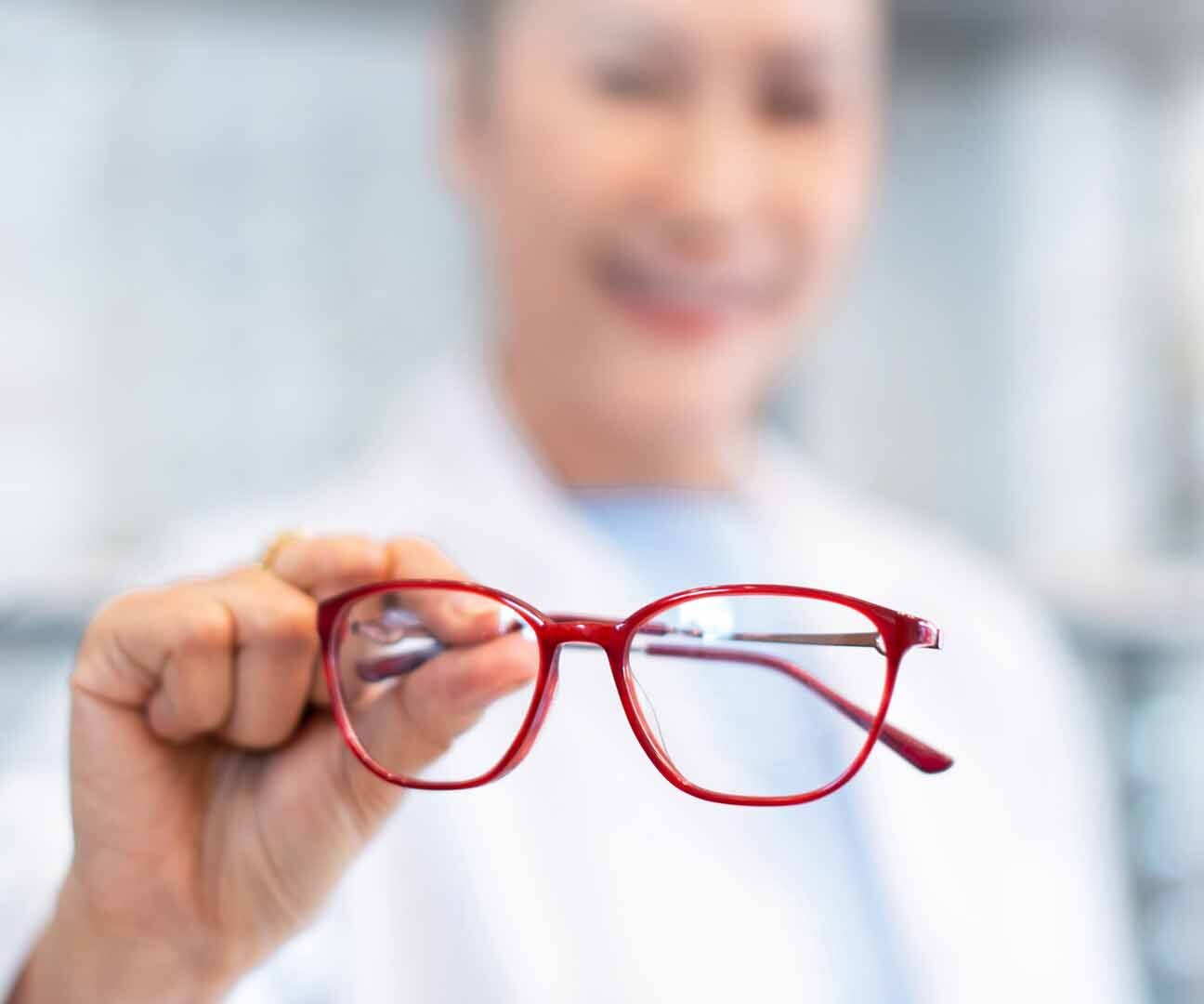 Opticien tenant des lunettes de vue rouges