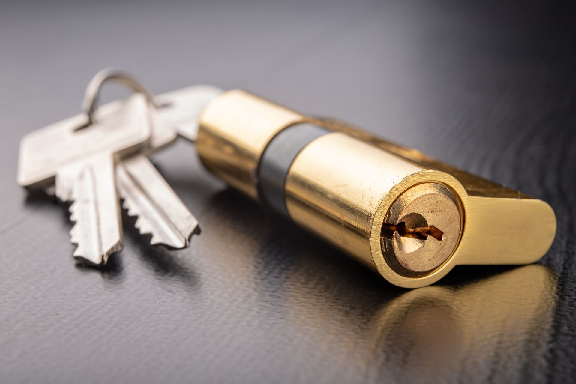Des clés à côté d'un cadenas doré sur une surface sombre