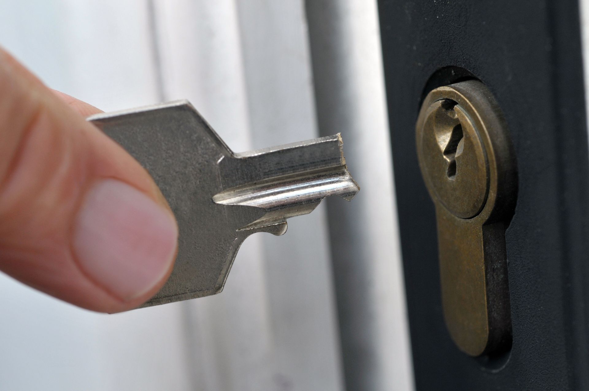 Une main tenant une clé près d'une serrure de porte noire sur un cadre de porte