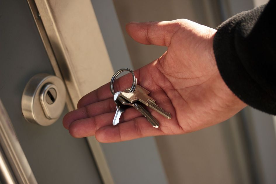 Main tenant les clés de la maison près d'une serrure