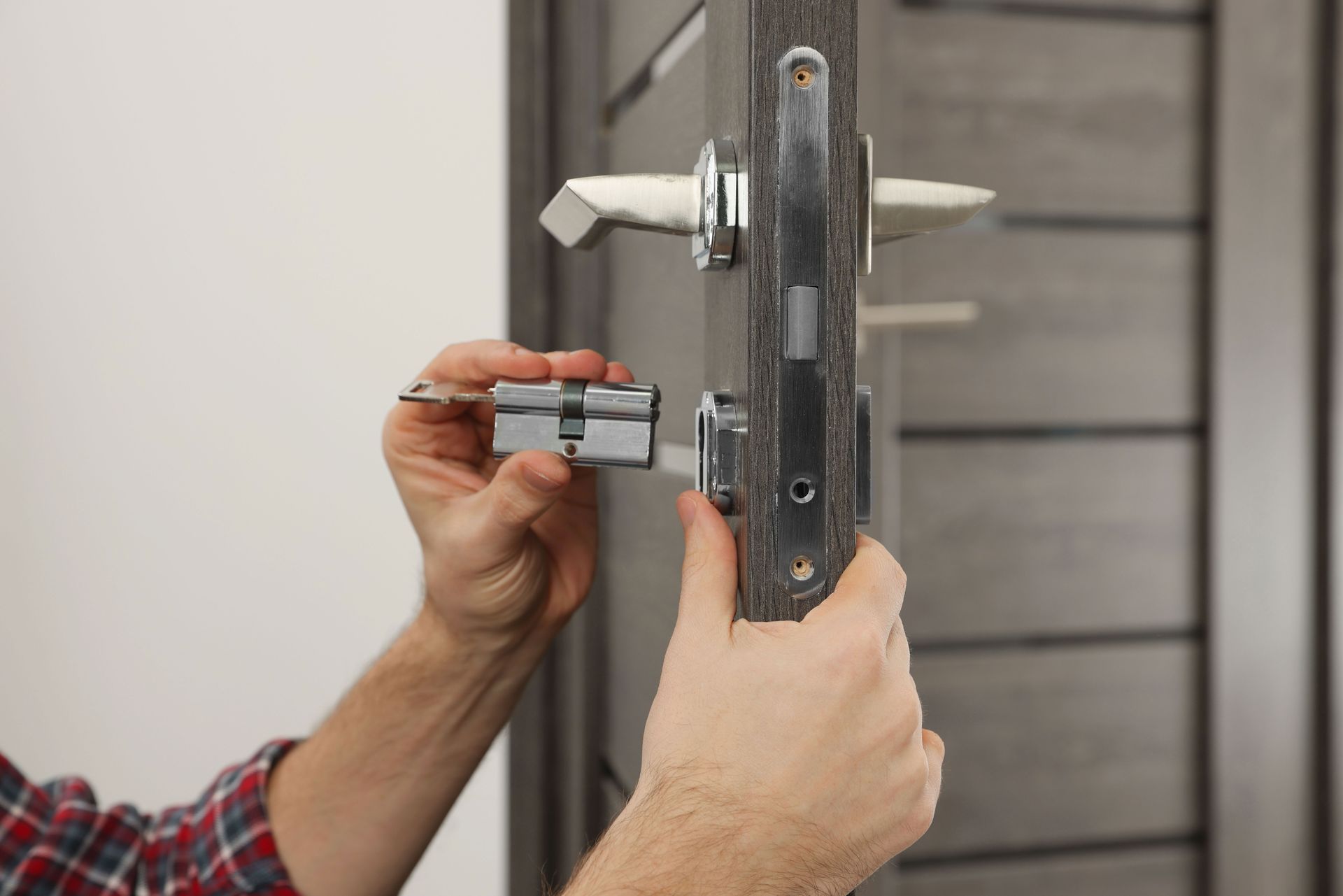 Mains installant une serrure sur une porte métallique grise avec un tournevis
