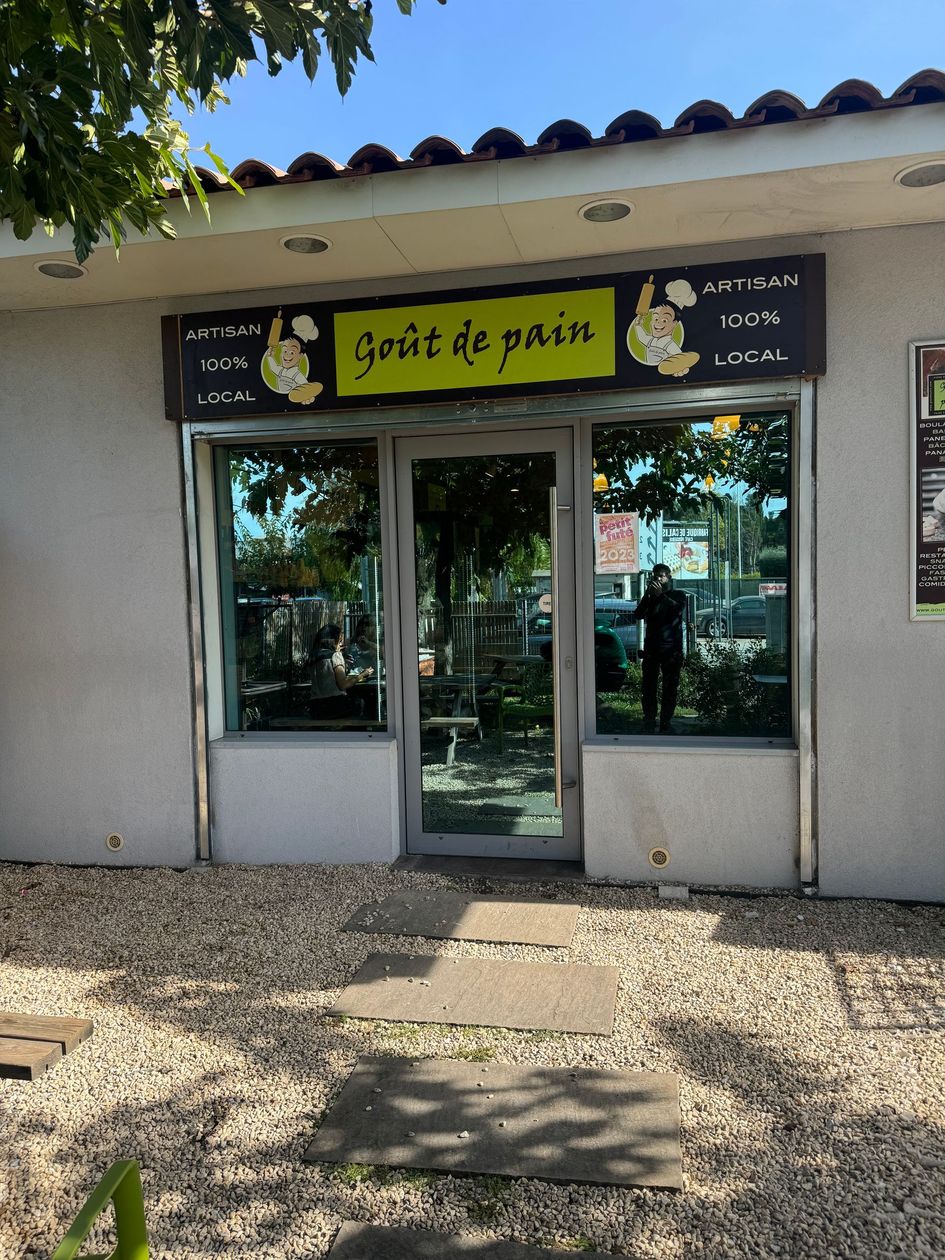 Entrée d'une petite boutique avec une enseigne jaune au-dessus de la porte.
