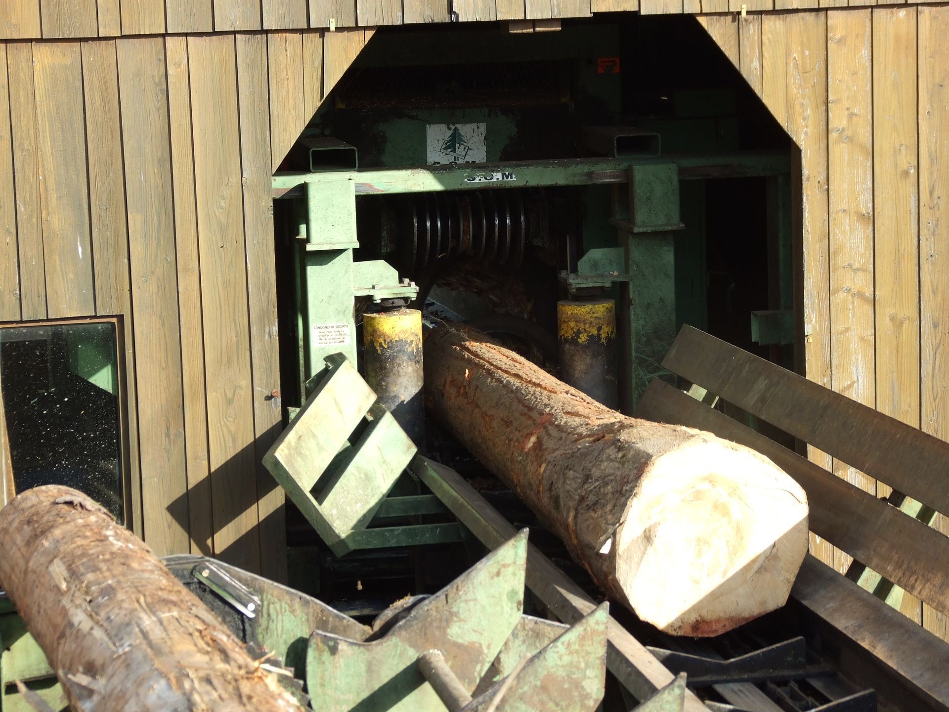 Planches de bois empilées, disposées en rangées alternées avec des espaces sombres entre elles.