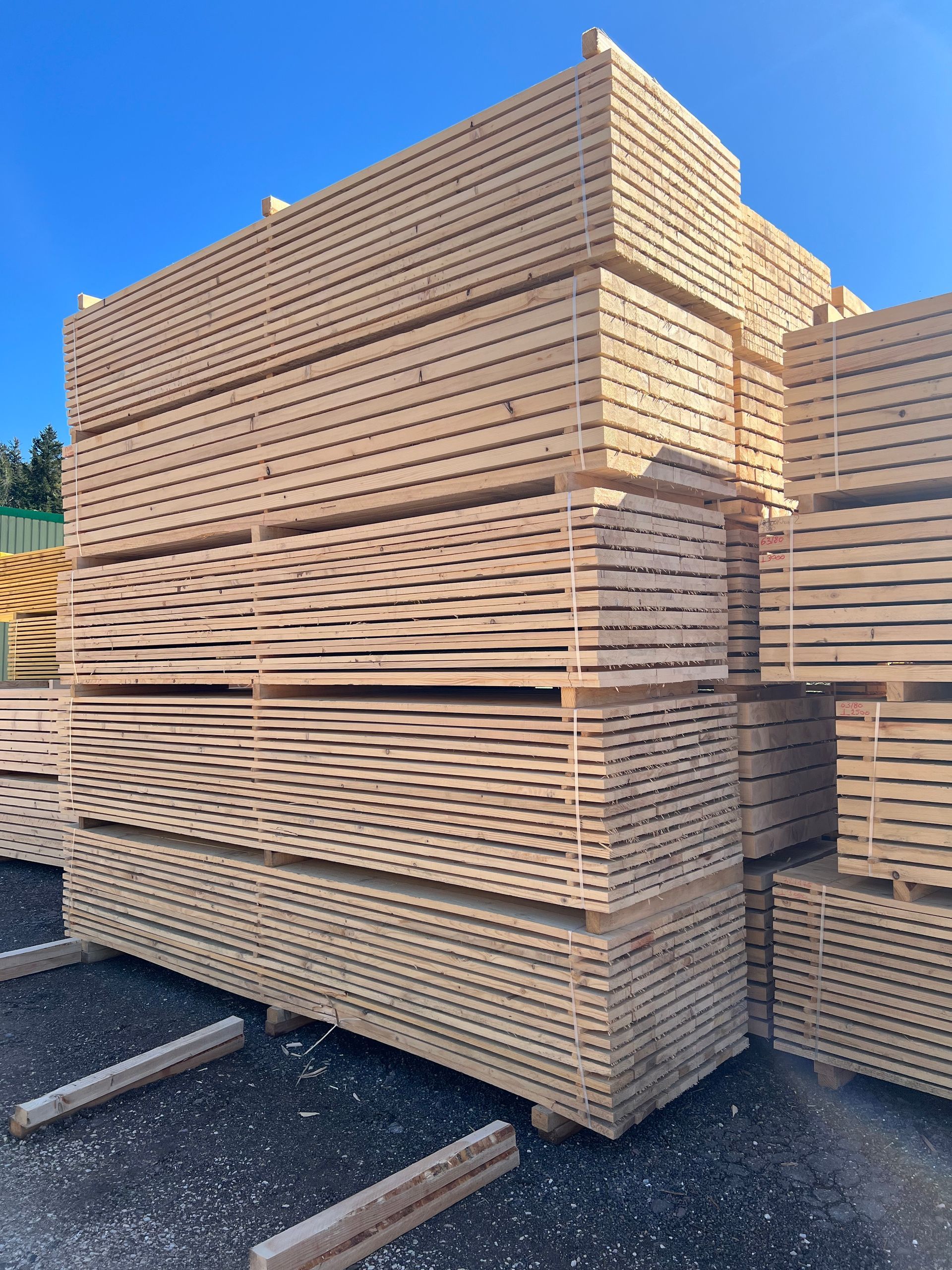 Des piles de planches de bois dans un entrepôt extérieur.