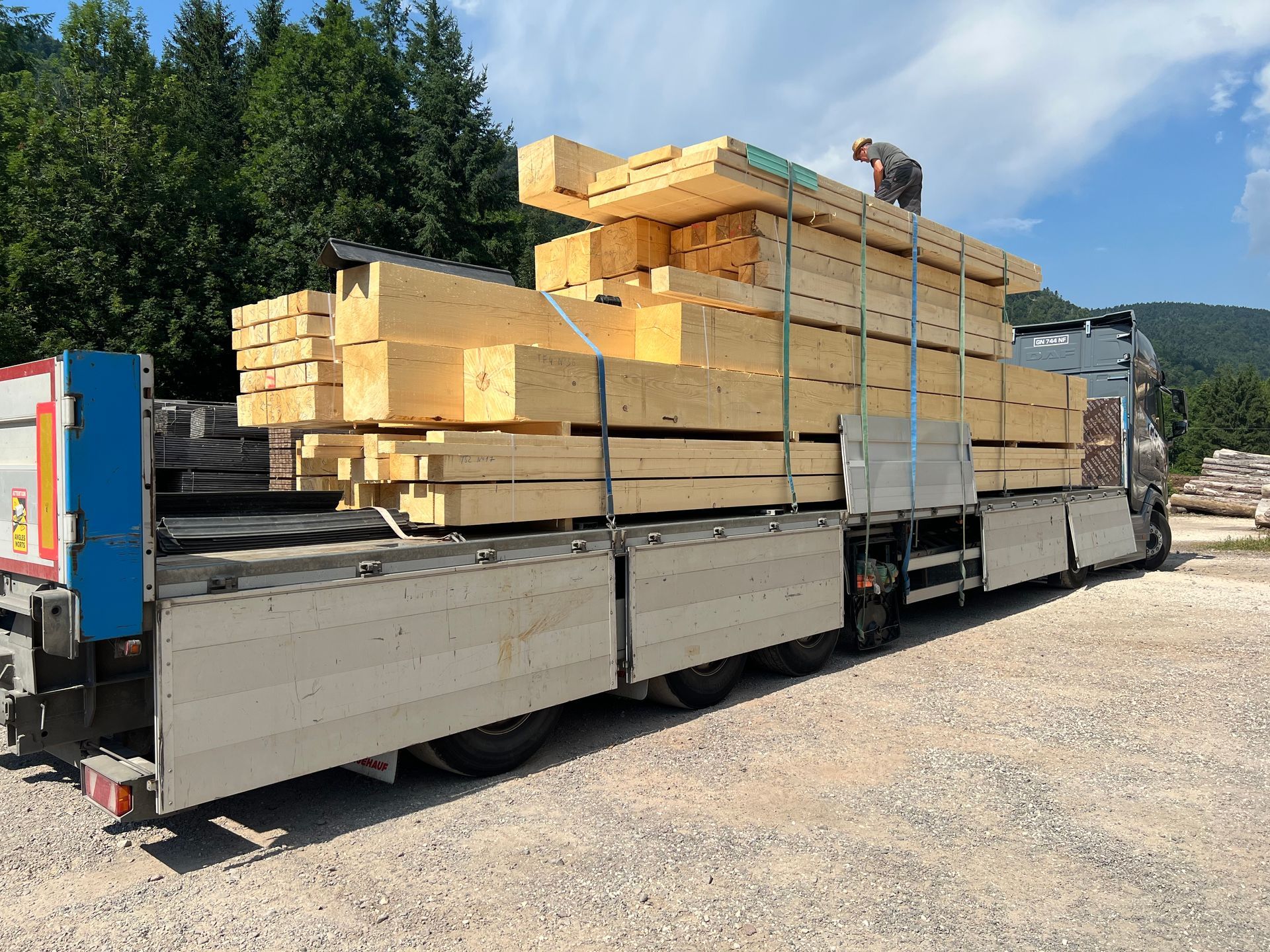 Camion plateau chargé de bois empilé.