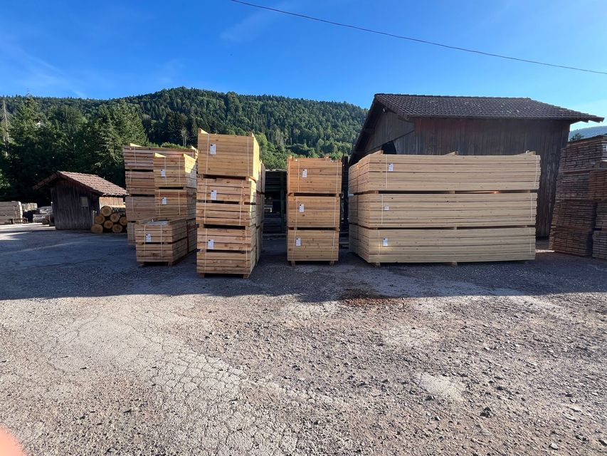 Des piles de planches de bois clair dans une scierie en plein air.