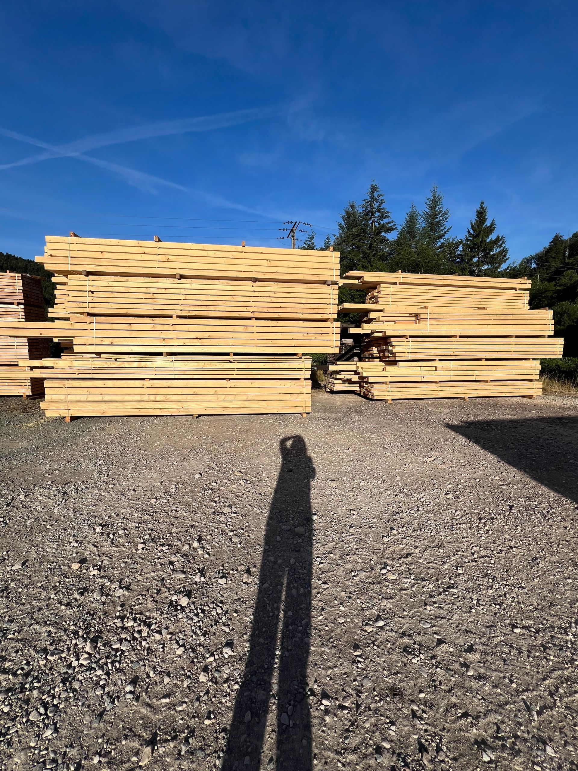 Un chariot élévateur dans une allée d'entrepôt, à côté de hautes piles de palettes et de cartons emballés.