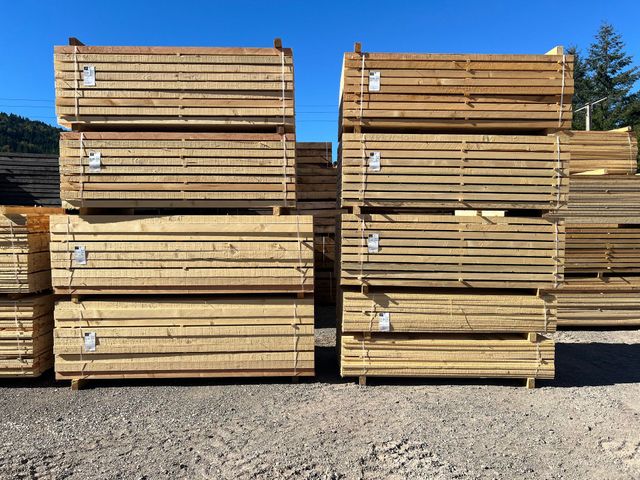 Des piles de planches de bois dans un entrepôt extérieur.
