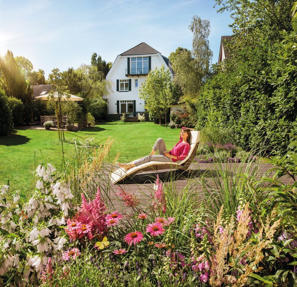 Ein Frau entspannt auf der Terrasse im Garten