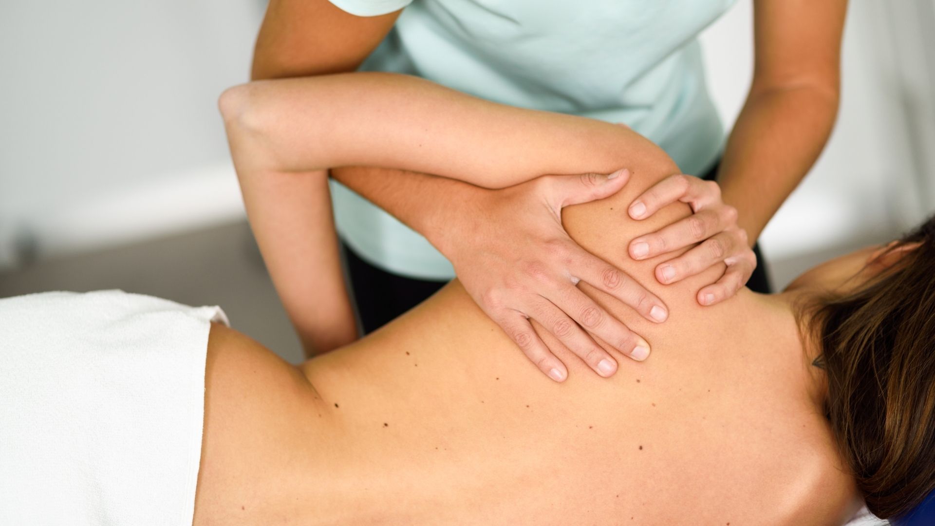 Masajista trabajando en el hombro de un paciente.