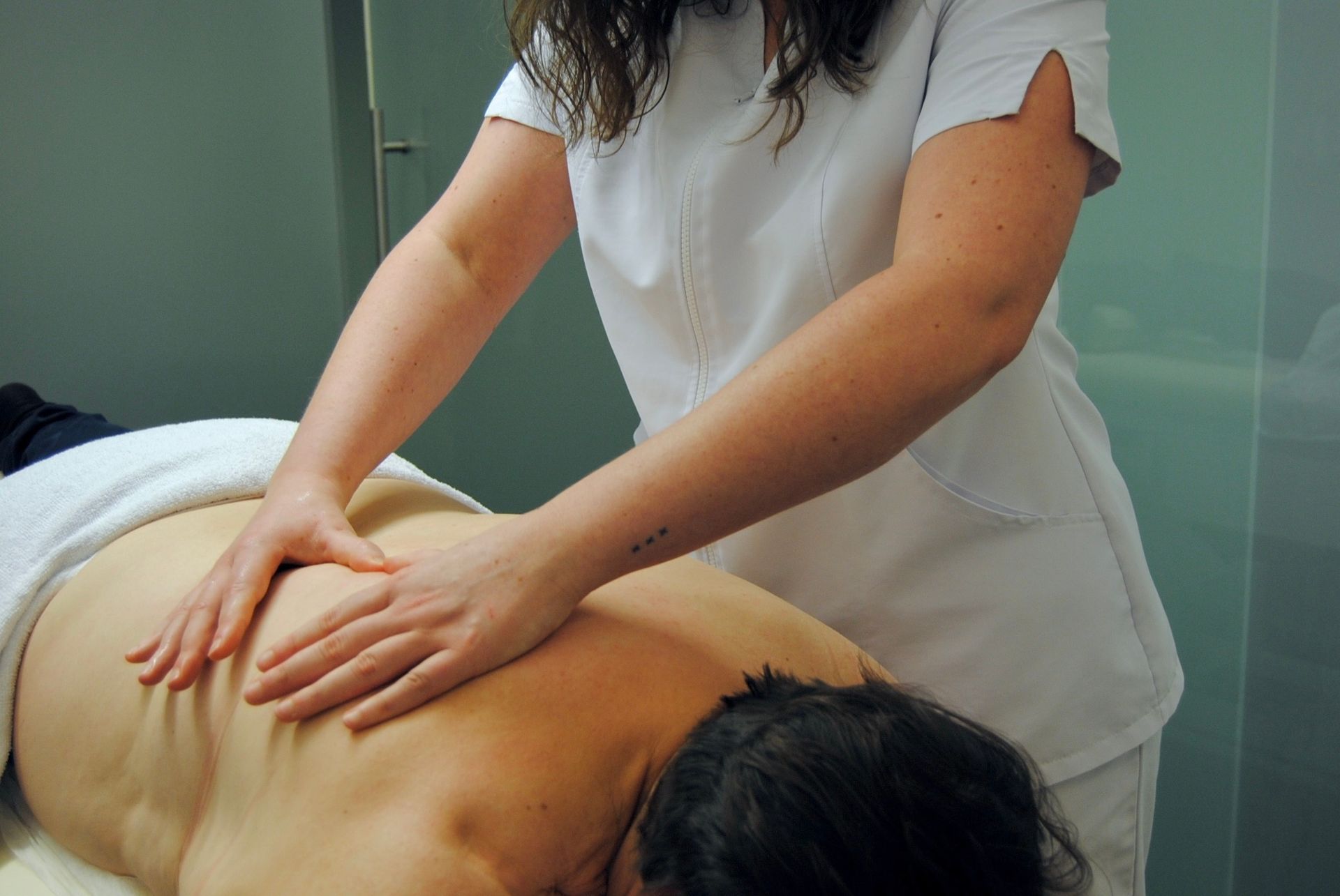 Una mujer con uniforme blanco le está dando un masaje a un hombre.